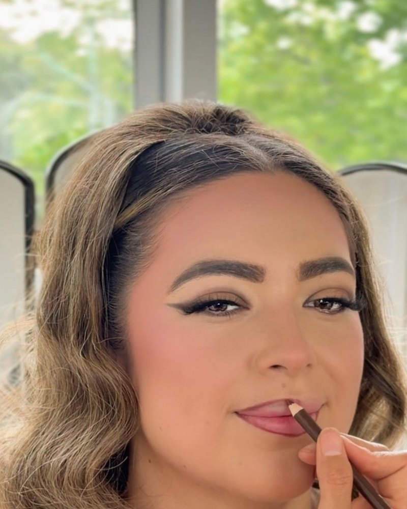 Thalia Castillo applying lip liner to a client